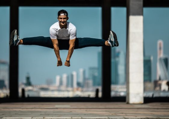 Man performing a split jump on concrete, showcasing fitness and agility.